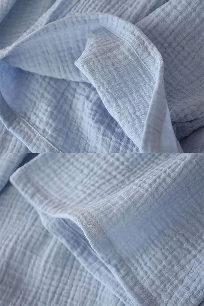 Tissu en gaze de coton bleu clair, avec un motif texturé et des plis délicats, évoquant le confort d'un kimono