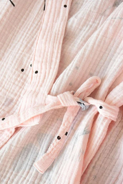 Kimono en gaze de coton rose clair avec des motifs noirs, noué à la taille pour un style doux et