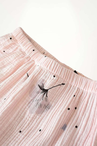 Un tissu en gaze de coton rose avec des motifs floraux noirs et des petits pois, doux et léger