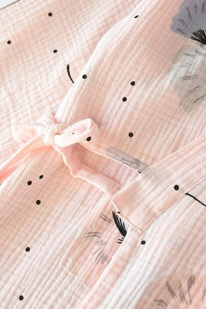 Détail d'un kimono en gaze de coton rose avec motifs floraux et pois noirs, noué à la taille