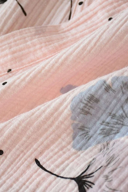 Tissu en gaze de coton rose avec motifs floraux bleus et noirs, offrant une texture douce et légère