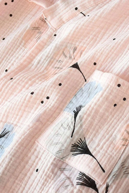 Tissu en gaze de coton rose avec motifs floraux noirs et bleus, offrant une texture douce et légère