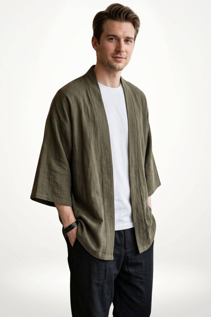 Homme portant un kimono moderne en lin vert olive avec un t-shirt blanc, dans un décor minimaliste