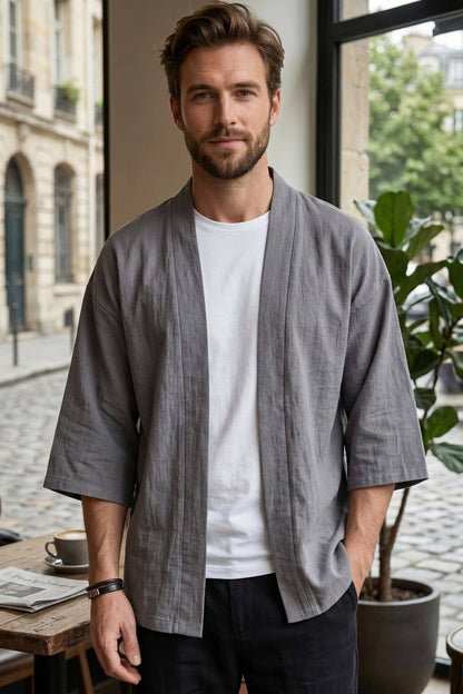Homme portant un kimono gris moderne, avec un t-shirt blanc, dans un décor urbain lumineux et végétal
