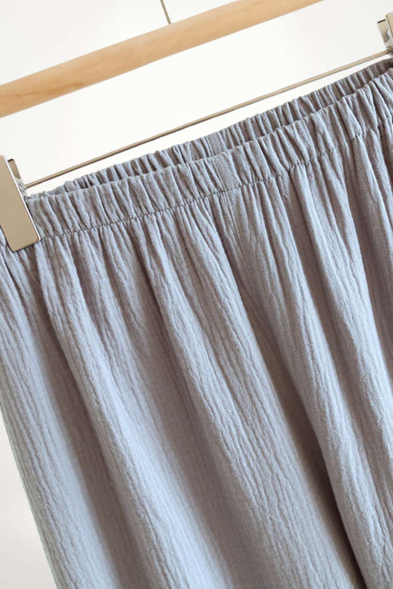 Pantalon en tissu léger gris, avec un motif texturé et une taille élastique, suspendu sur un cintre
