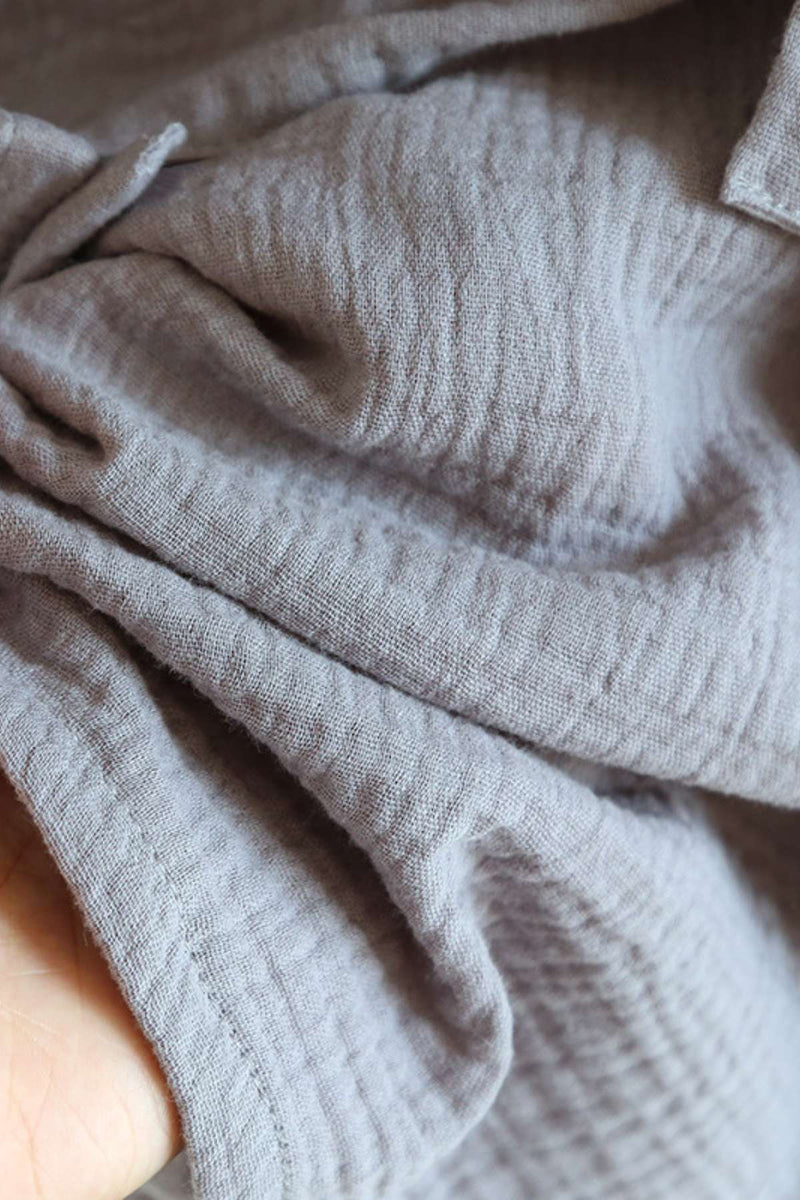 Tissu gris doux et texturé, plié avec des ombres légères, évoquant un style japonais confortable et apaisant