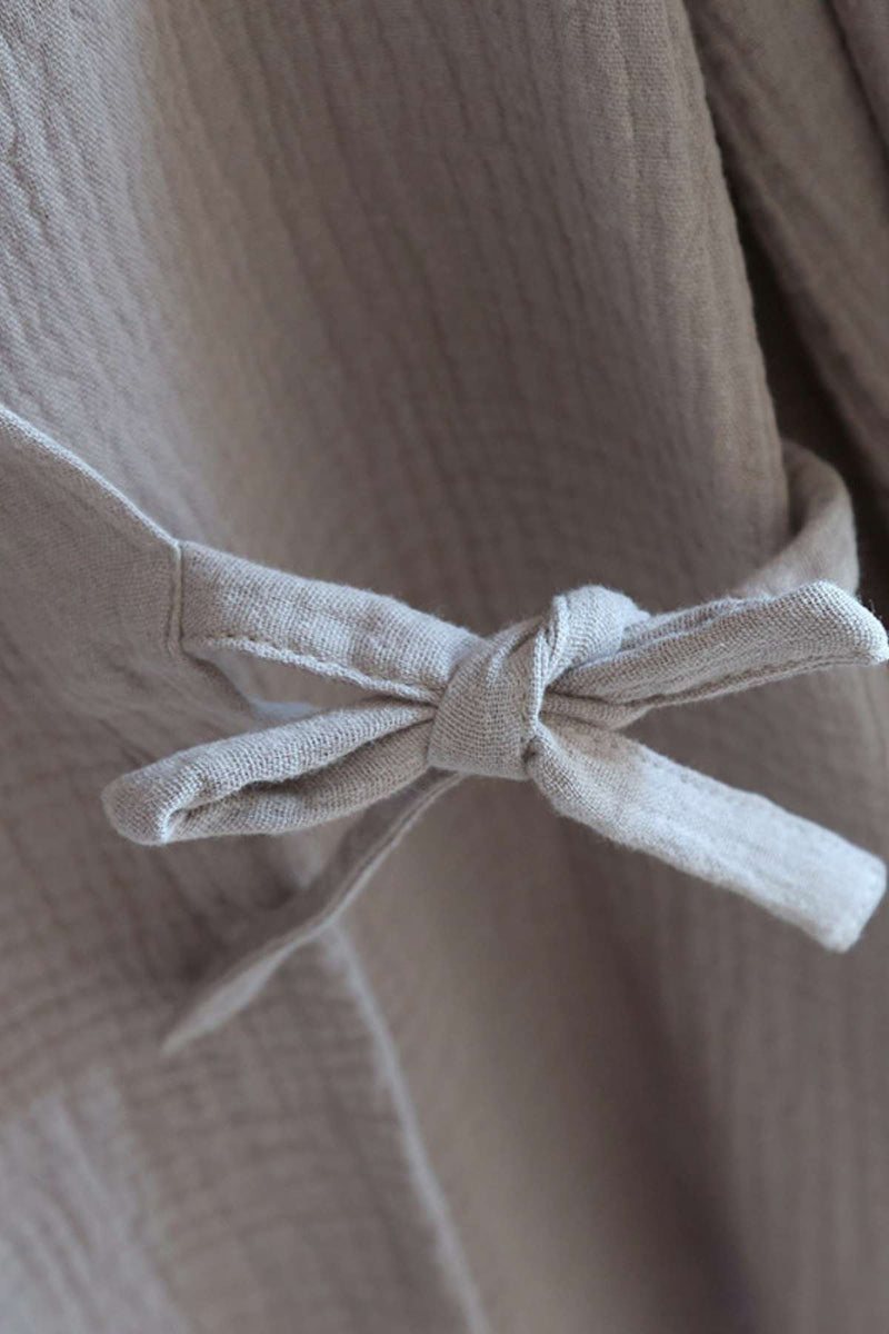 Un nœud en tissu beige sur un kimono en matière légère, créant une ambiance douce et réconfortante