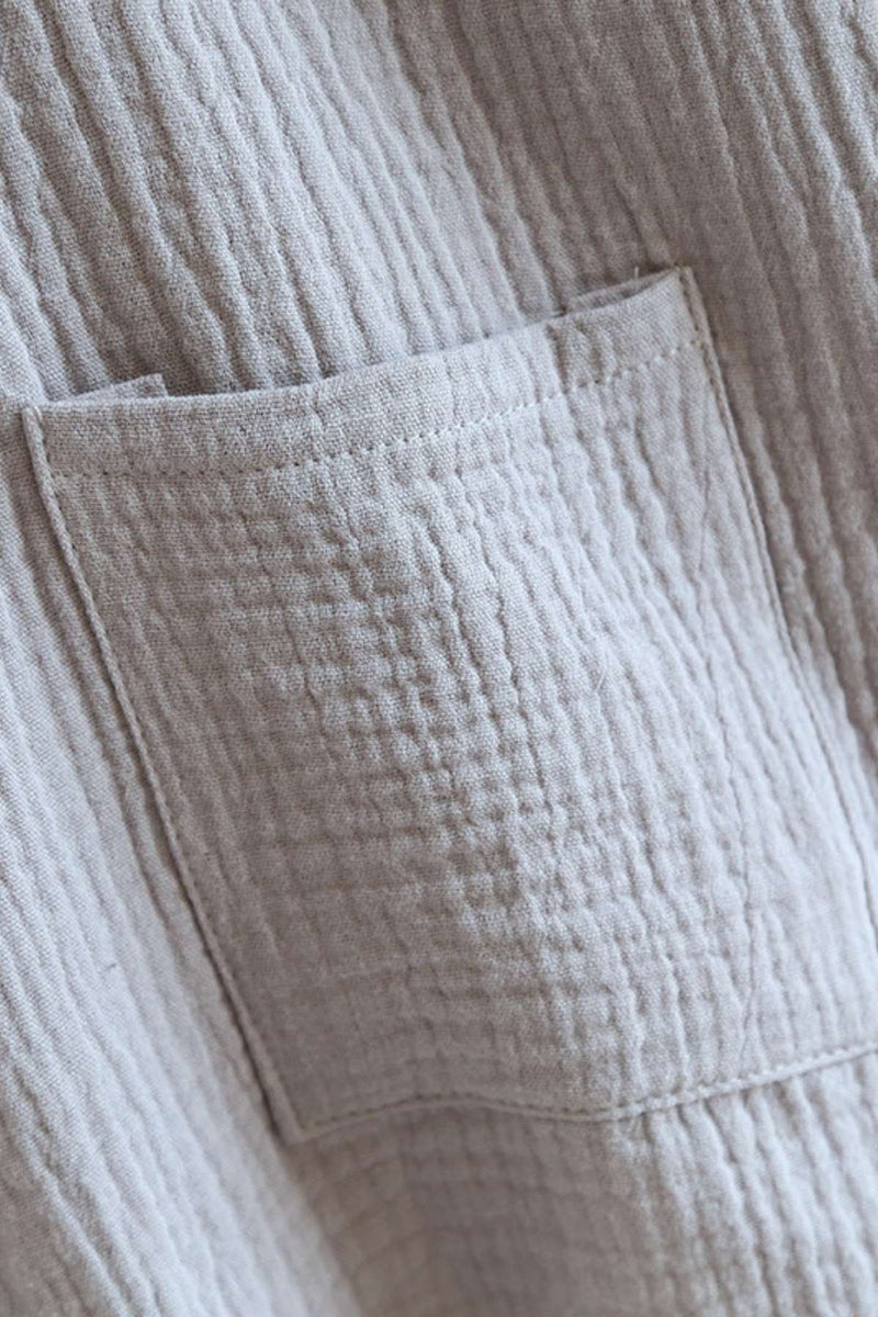 Tissu texturé beige avec un motif gaufré et une poche visible sur le devant, évoquant un style japonais