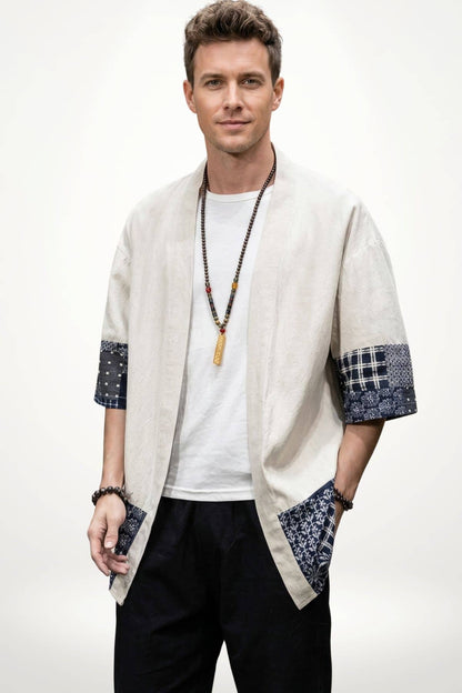 Homme portant un kimono beige avec des manches à motifs bleus, posé sur un fond blanc