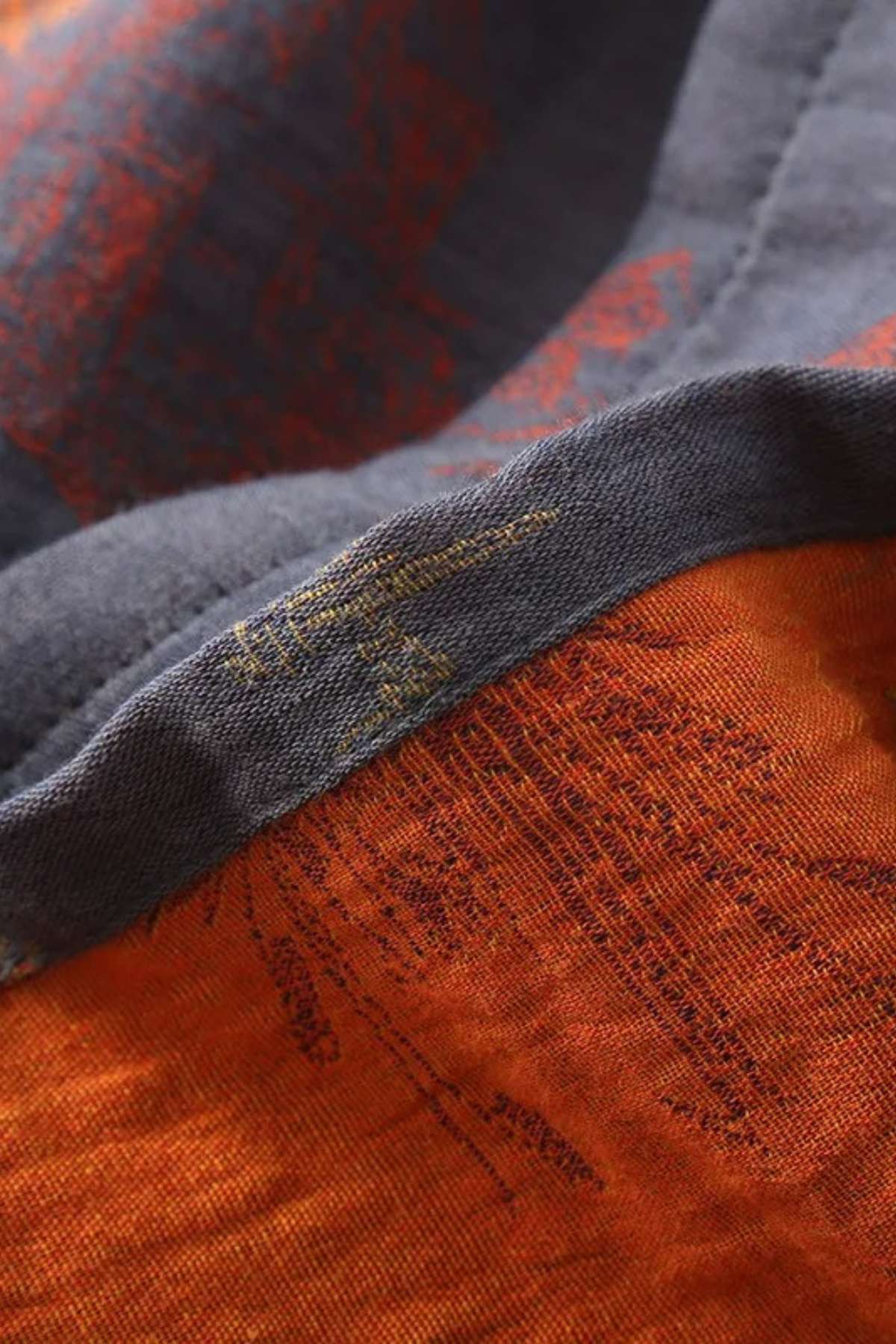 Détail d'un kimono japonais avec des motifs rouges et orange sur un fond gris, mettant en valeur la texture du
