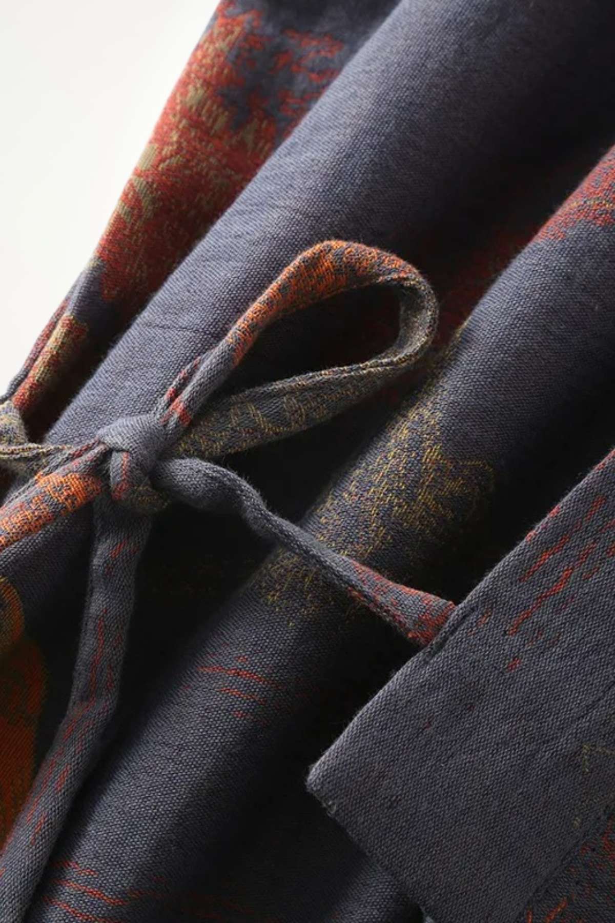 Un kimono japonais en tissu sombre avec des motifs rouges et dorés, noué délicatement à la taille