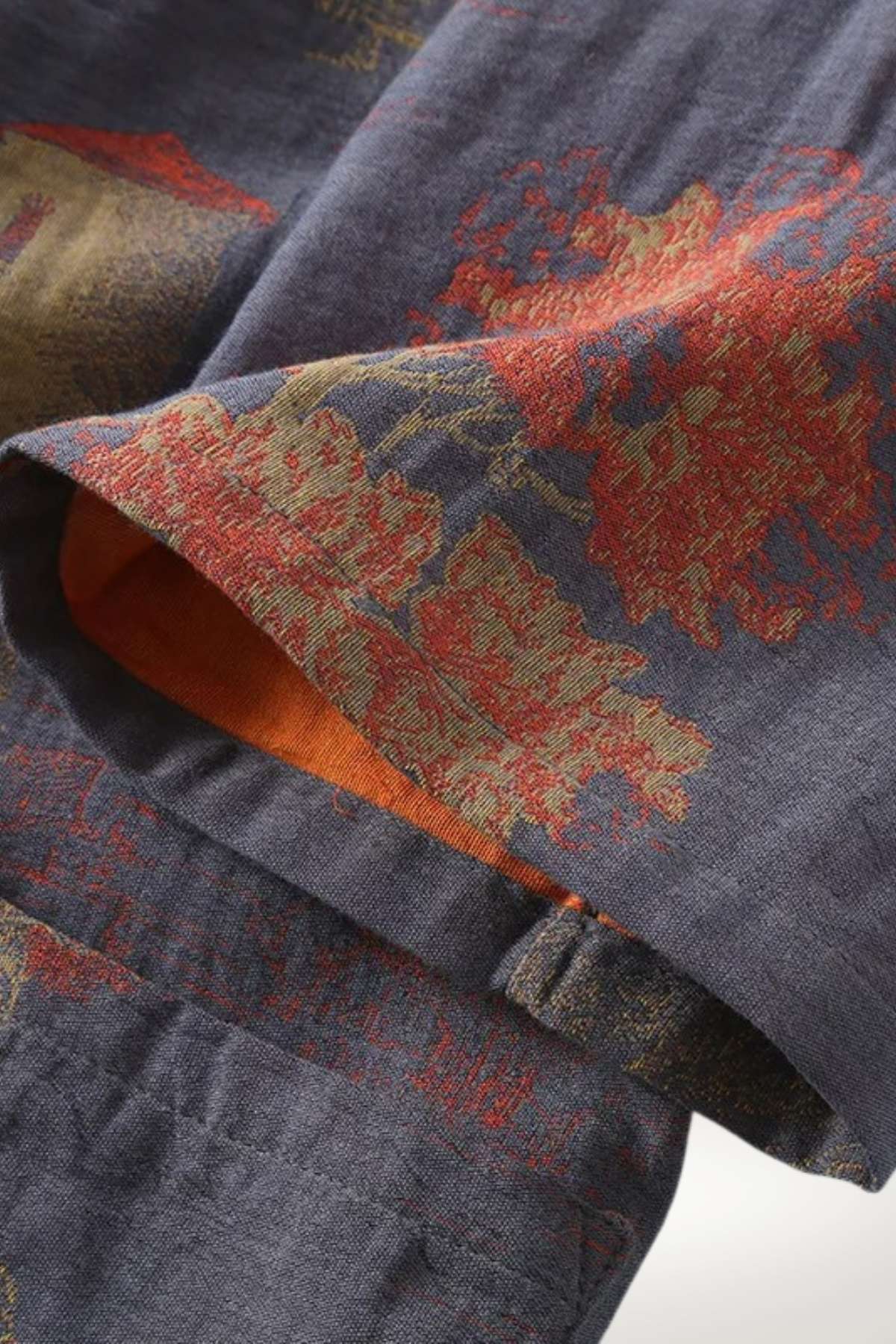 Détails d'un kimono japonais en tissu bleu foncé avec motifs floraux rouges et dorés, doublure orange visible