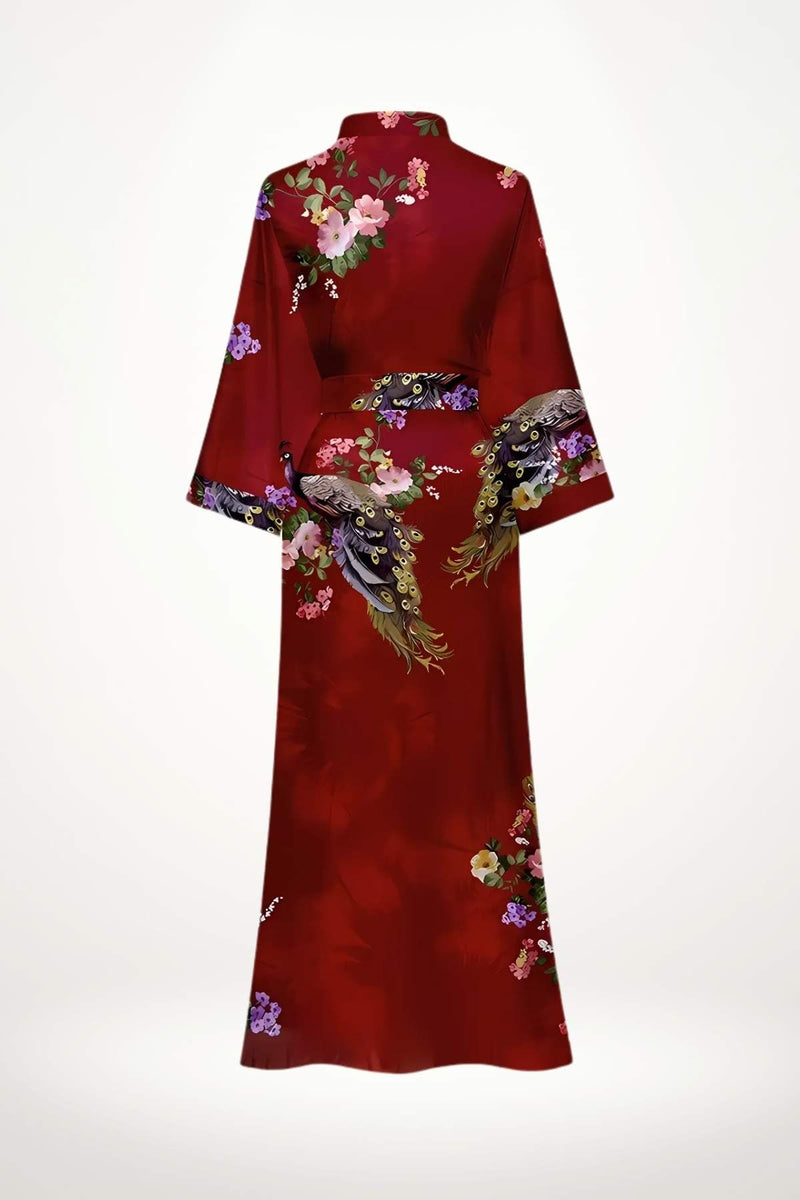 Kimono long en satin rouge avec motifs floraux colorés et détails de paon, évoquant l'élégance nocturne