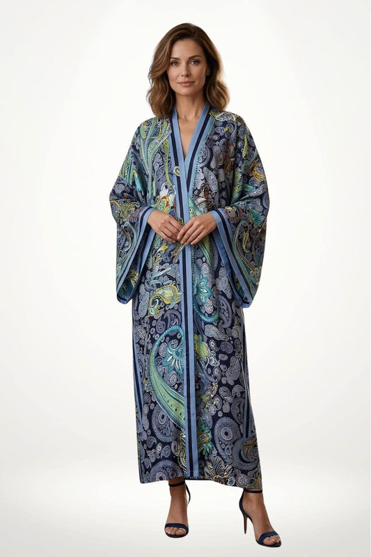 Femme portant un long kimono aux motifs colorés sur fond bleu, avec des manches larges et un décor minimaliste
