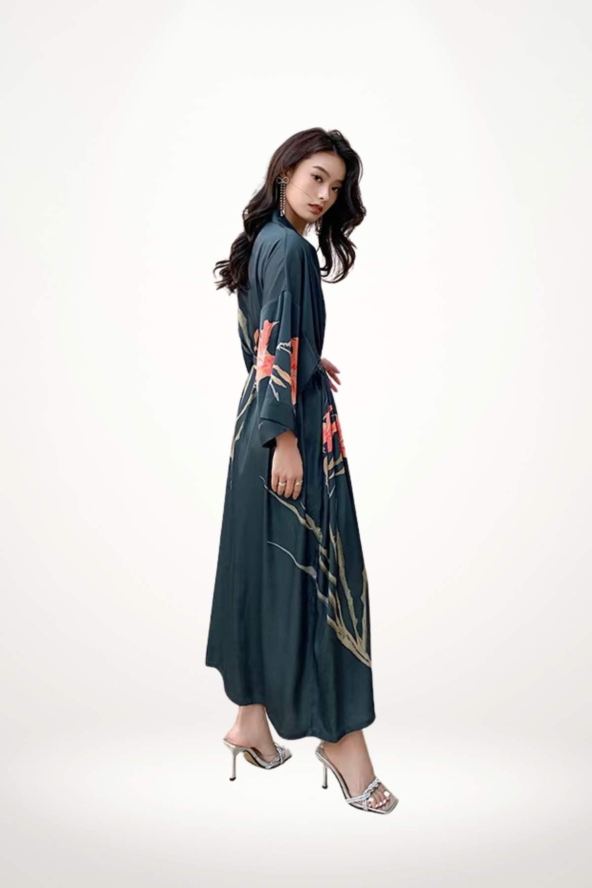 Femme en kimono long bleu foncé avec motifs floraux, posant élégamment sur un fond neutre