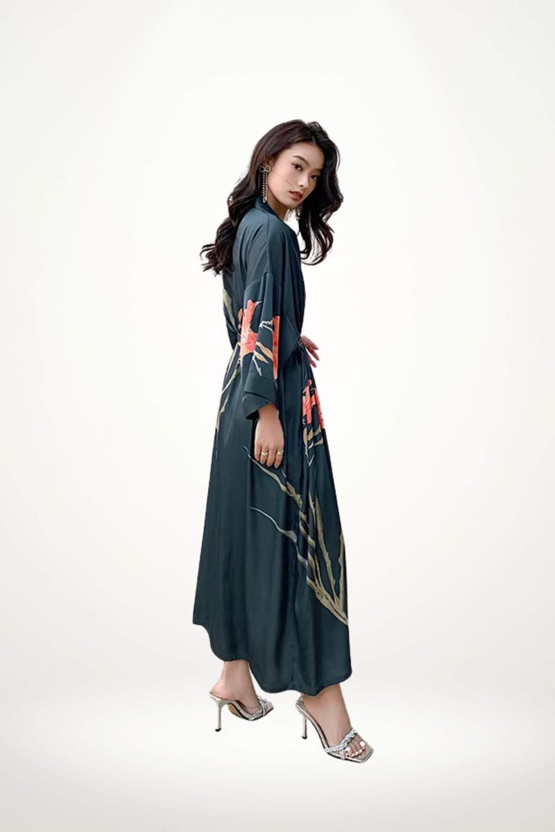 Femme en kimono long bleu foncé avec motifs floraux, posant élégamment sur un fond neutre