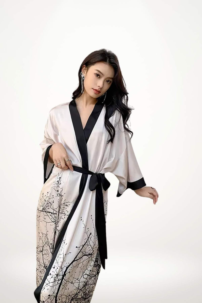 Femme portant un kimono long en satin blanc avec des motifs noirs, élégant et fluide, sur fond neutre