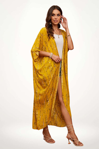 Kimono jaune à motifs, ample et fluide, porté par une femme en posture décontractée sur fond clair