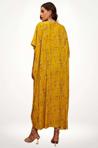 Femme portant un kimono jaune à motifs, avec des sandales, dans une posture décontractée sur fond clair