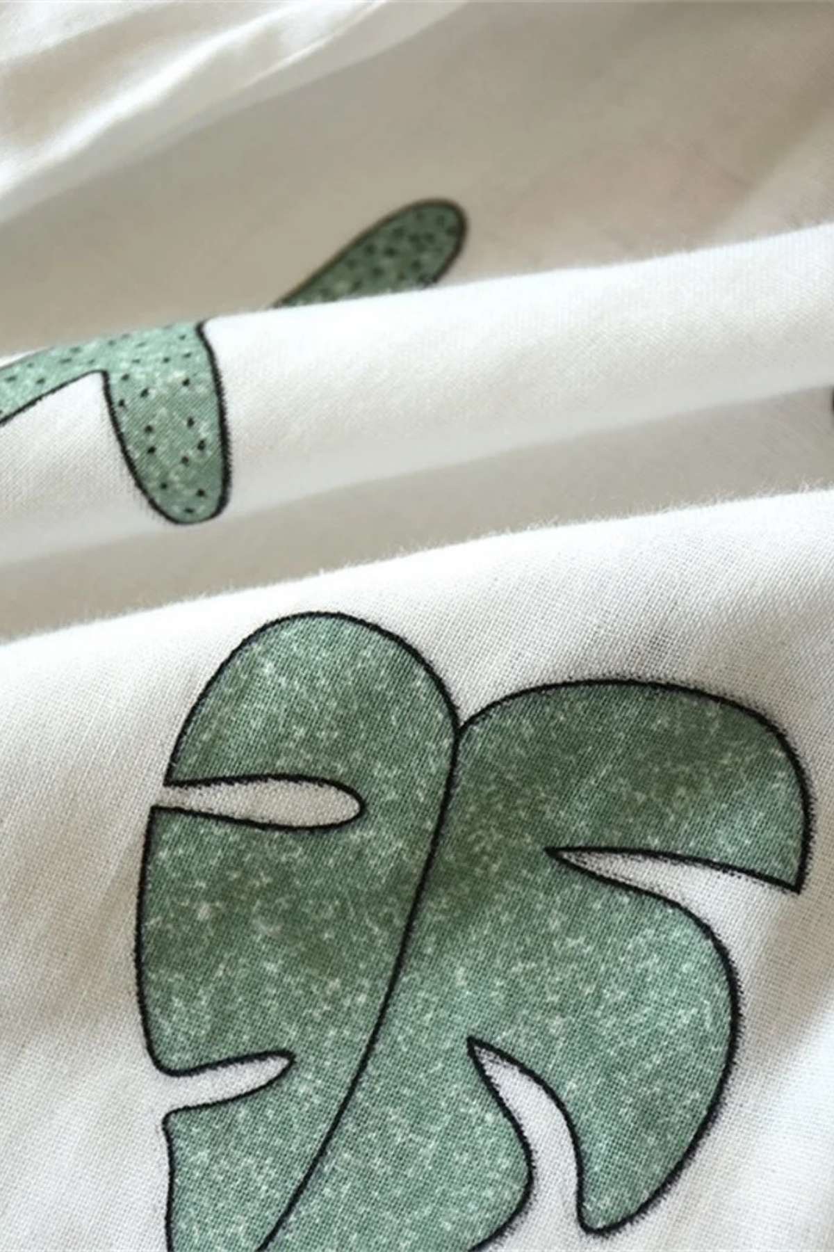 Tissu en coton blanc avec motifs de feuilles vertes et contours noirs, évoquant un style japonais léger et frais