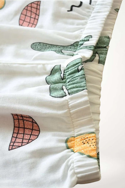 Détail d'un kimono en coton à manches courtes avec motifs colorés de fruits et cactus sur fond blanc