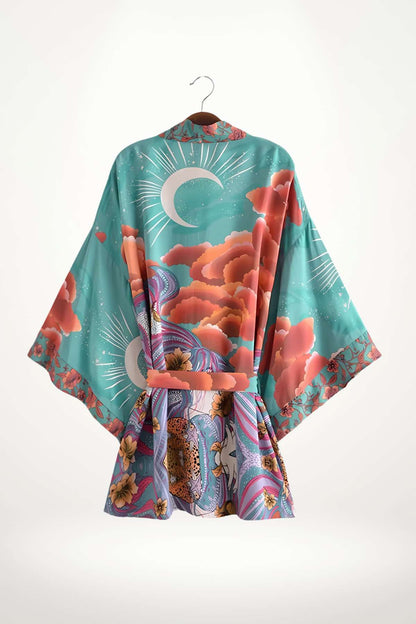 Kimono mi-long aux motifs floraux colorés, dominé par des teintes turquoise et roses, suspendu sur un cintre