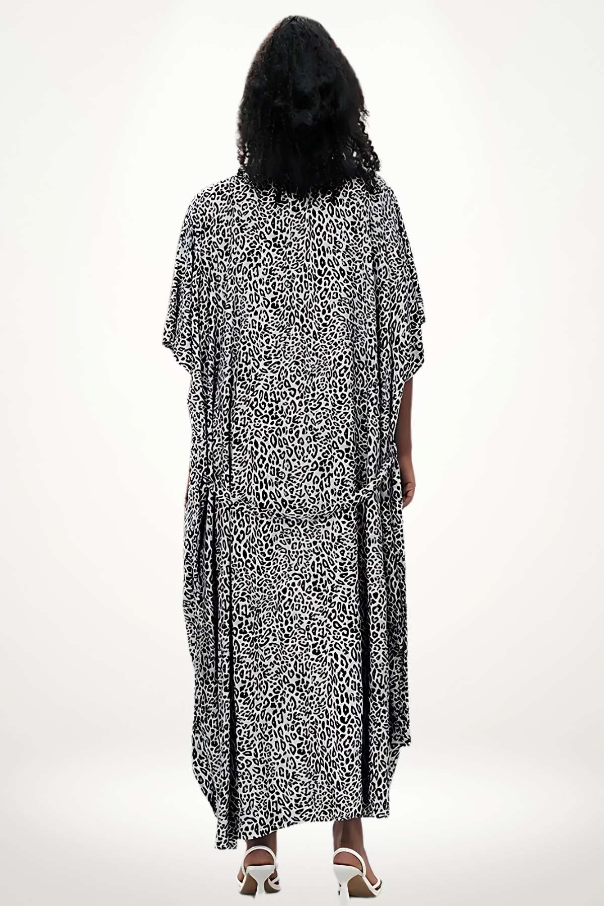 Kimono à motifs léopard noir et blanc, drapé élégant, porté par une femme aux cheveux bouclés, fond neutre