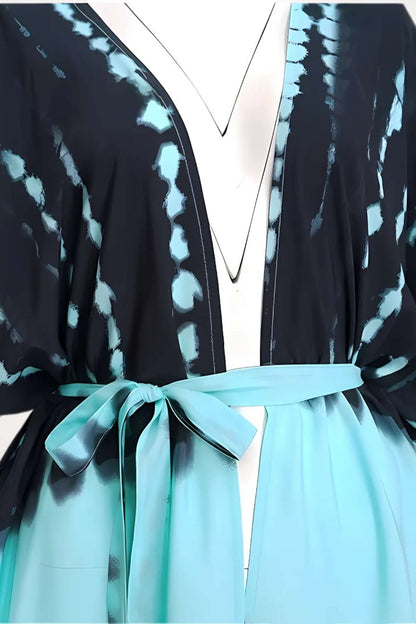 Kimono en tissu léger avec des motifs bleu et noir, ceinturé d'un ruban turquoise, évoquant l'élégance estivale