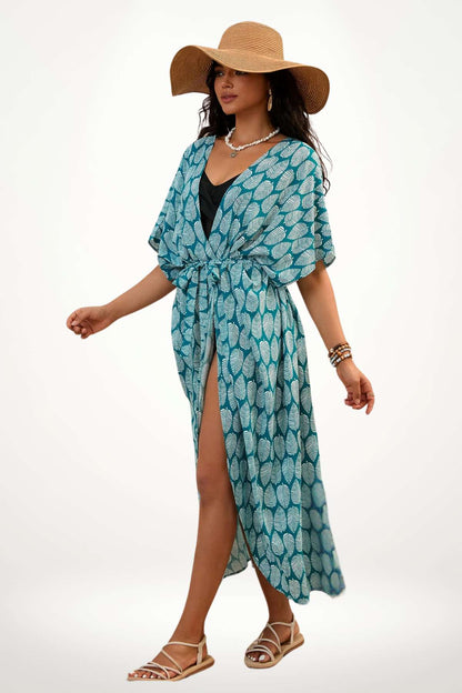 Femme en kimono bleu à motifs de feuilles, portant un chapeau de paille, marchant sur un fond clair