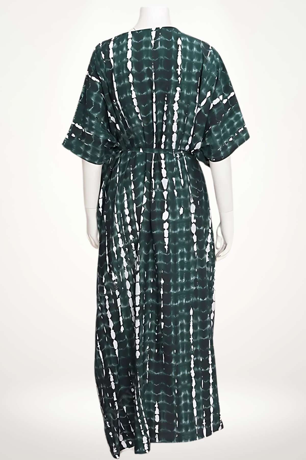 Kimono long en tissu léger, vert foncé avec motifs blancs, porté à la plage sous un ciel ensoleillé