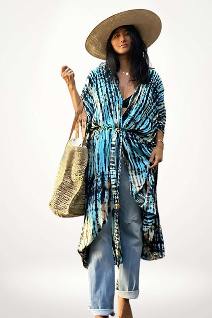 Femme portant un kimono aux motifs bleus et beiges, chapeau en paille, sac en osier, devant un fond clair