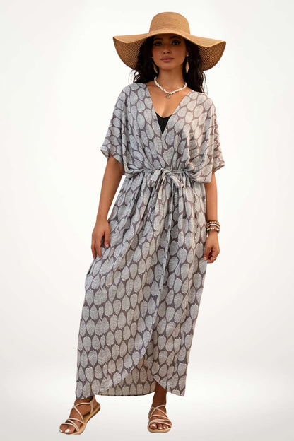 Femme portant un kimono à motifs de feuilles grises, avec un chapeau large et des sandales, sur fond clair