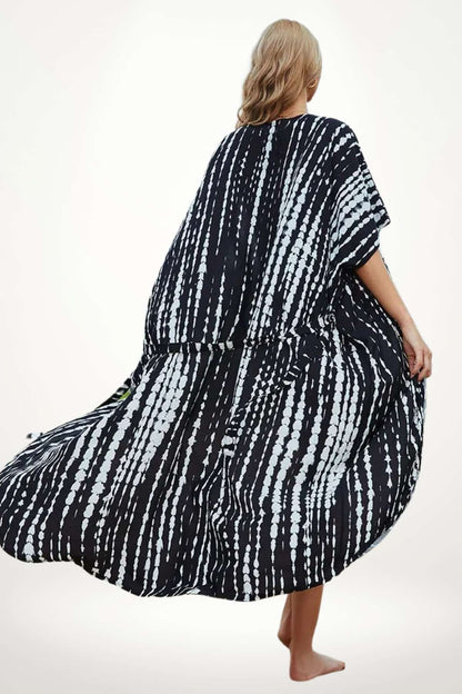 Kimono aérien noir et blanc avec motifs à rayures, porté par une femme debout sur un fond neutre