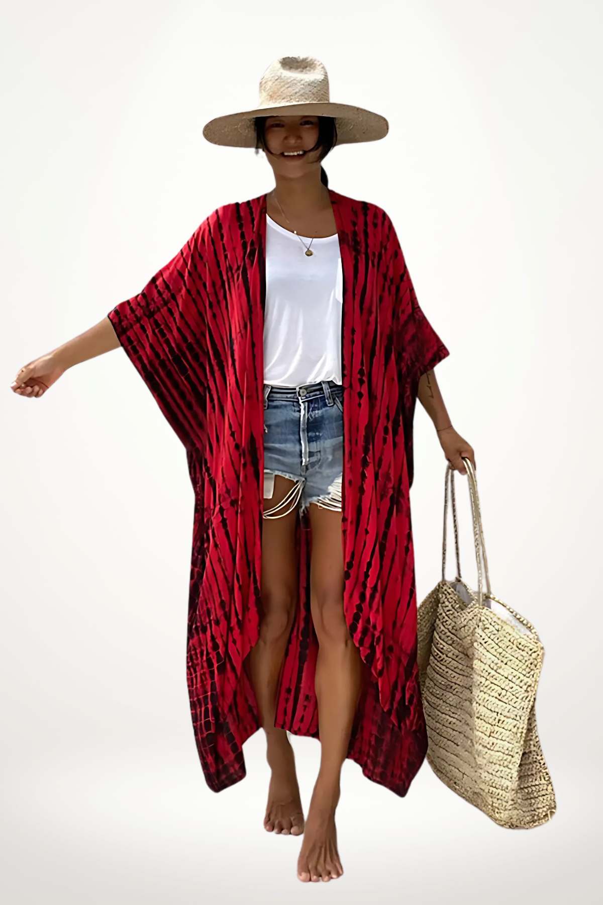 Femme souriante portant un kimono rouge à motifs, un t-shirt blanc, un short en jean et un grand sac en