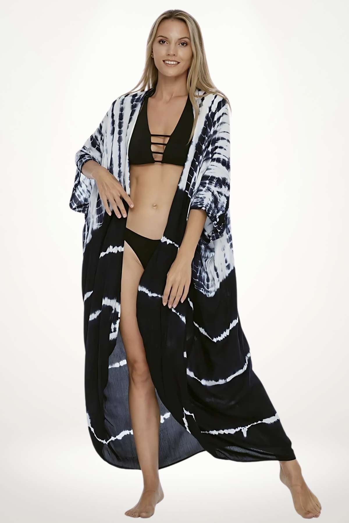 Femme souriante portant un kimono noir et blanc à motifs tie-dye, avec un bikini noir en dessous