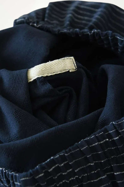 Intérieur d'un kimono pyjama pour homme, en tissu noir uni avec des motifs rayés subtils et une étiquette beige