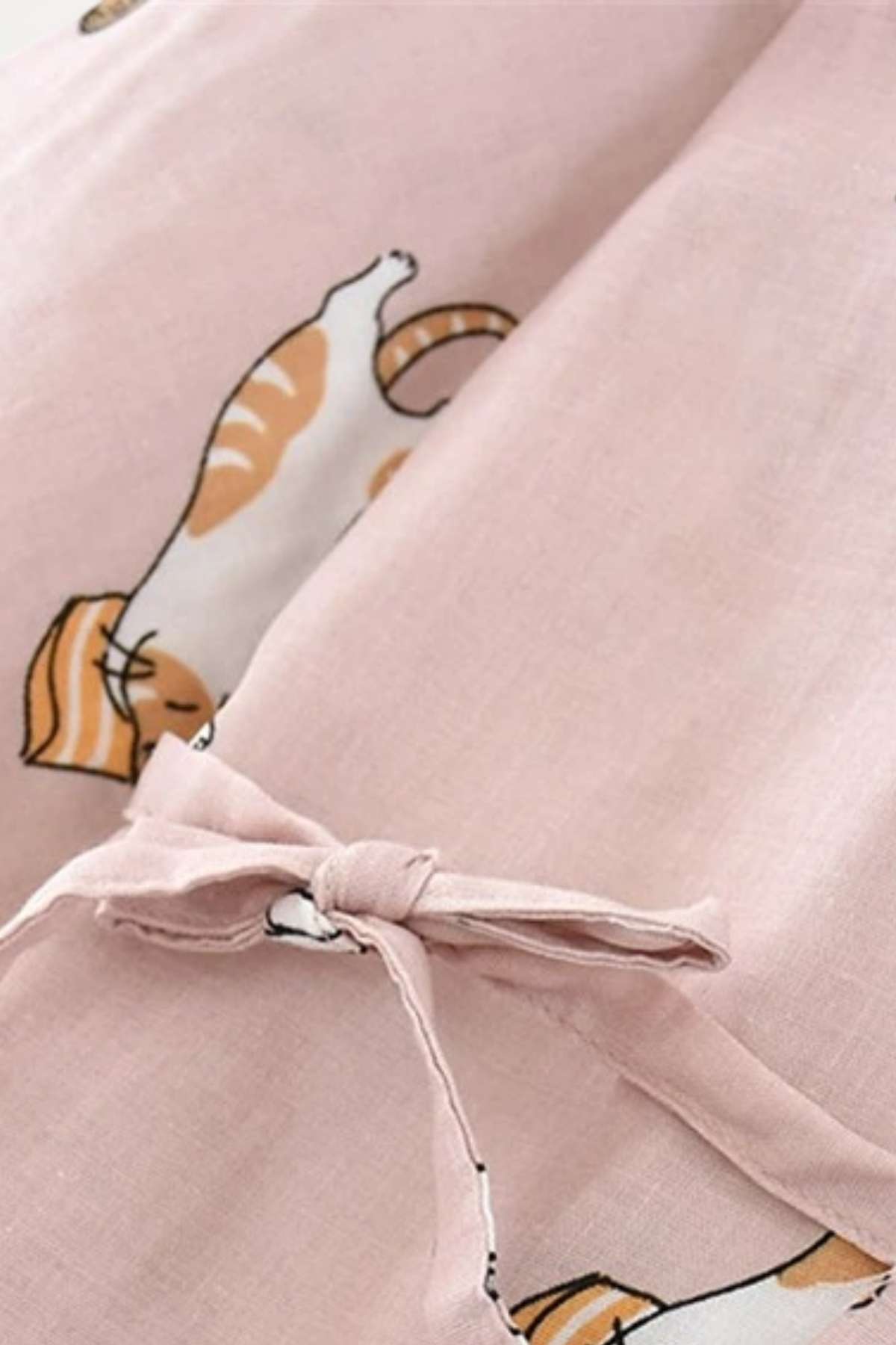 Tissu léger rose avec motifs de chats, noué sur le devant, évoquant un style décontracté et confortable