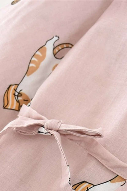 Tissu léger rose avec motifs de chats, noué sur le devant, évoquant un style décontracté et confortable