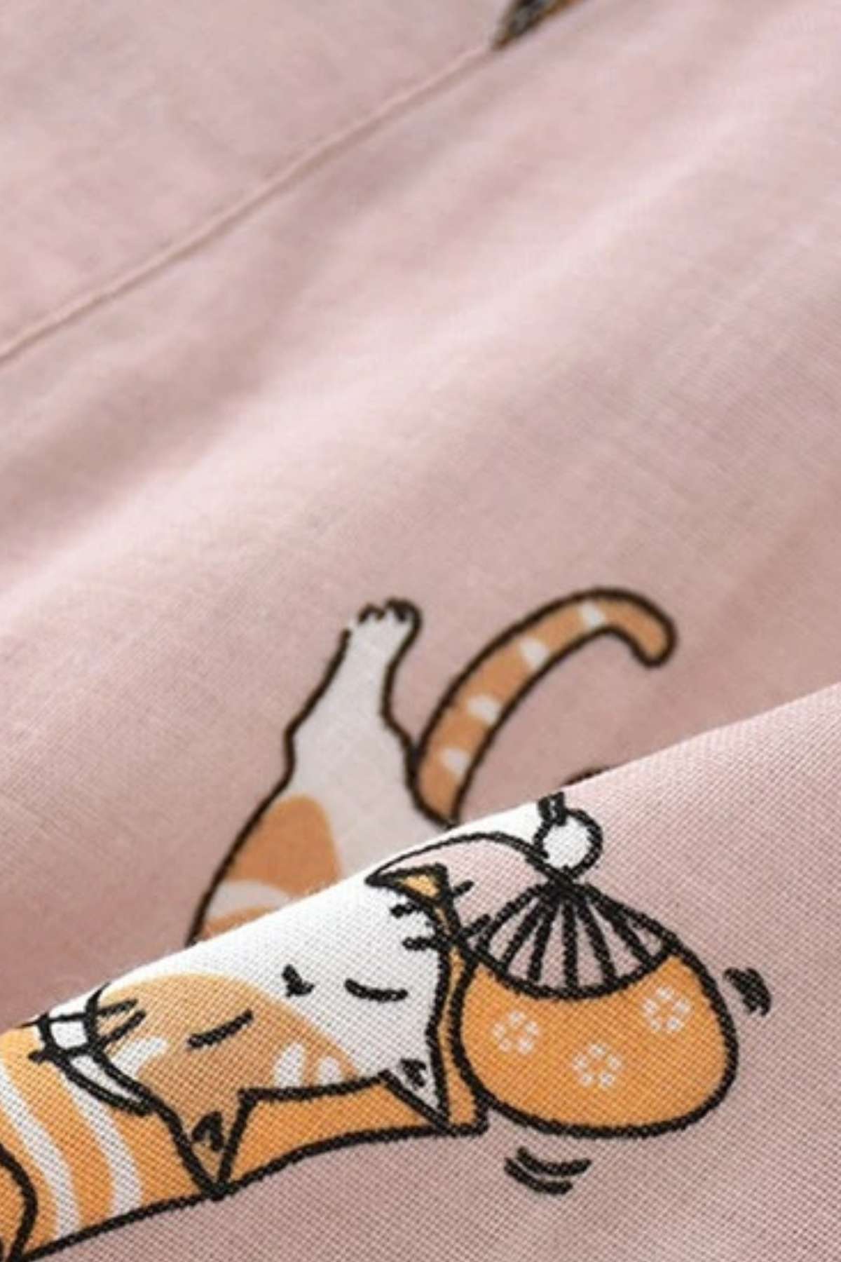 Tissu léger de kimono rose avec motifs de chats endormis et accessoires colorés, créant une ambiance décontractée