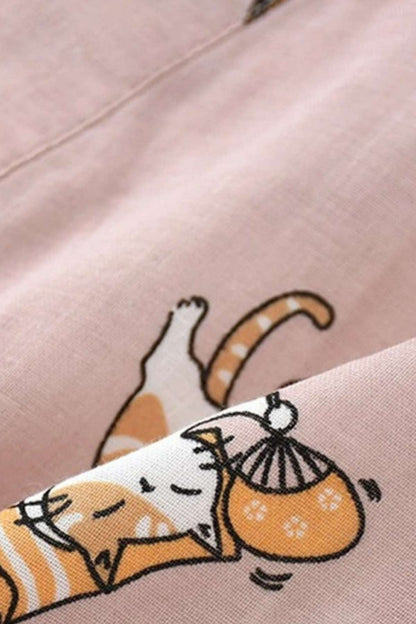 Tissu léger de kimono rose avec motifs de chats endormis et accessoires colorés, créant une ambiance décontractée