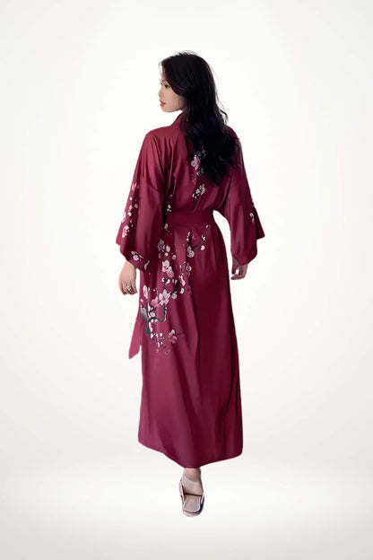 Femme portant un kimono rouge avec des motifs floraux, vue de dos, sur fond blanc