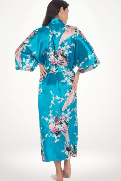 Femme portant un kimono bleu vif avec des motifs de fleurs et de paons, dans un décor minimaliste