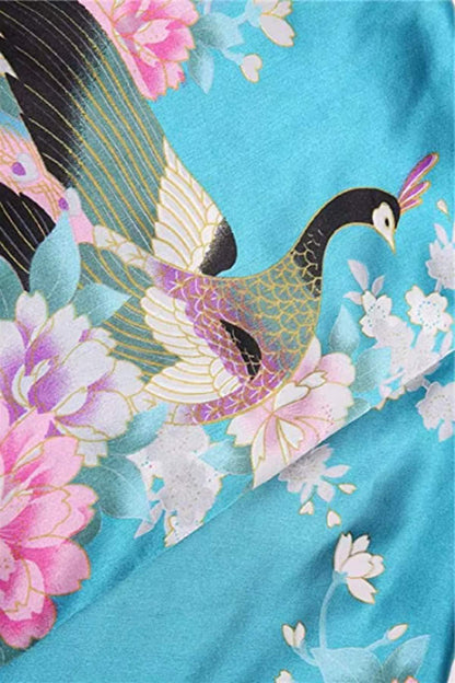 Tissu en satin turquoise orné de motifs floraux roses et d'un paon aux plumes dorées et noires