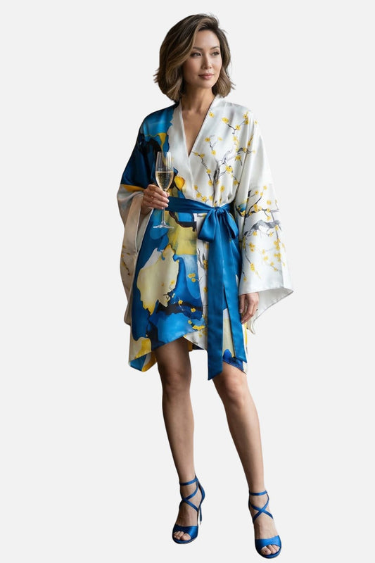Femme en kimono satin blanc et bleu, motifs floraux, tenant une coupe de champagne, dans un décor minimaliste