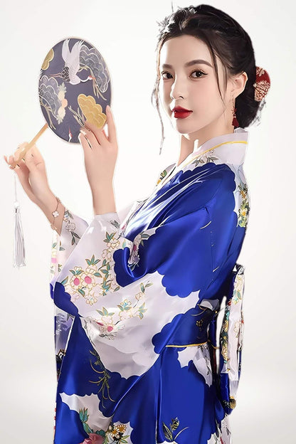 Femme en kimono satin bleu aux motifs floraux, tenant un éventail, avec un fond blanc lumineux