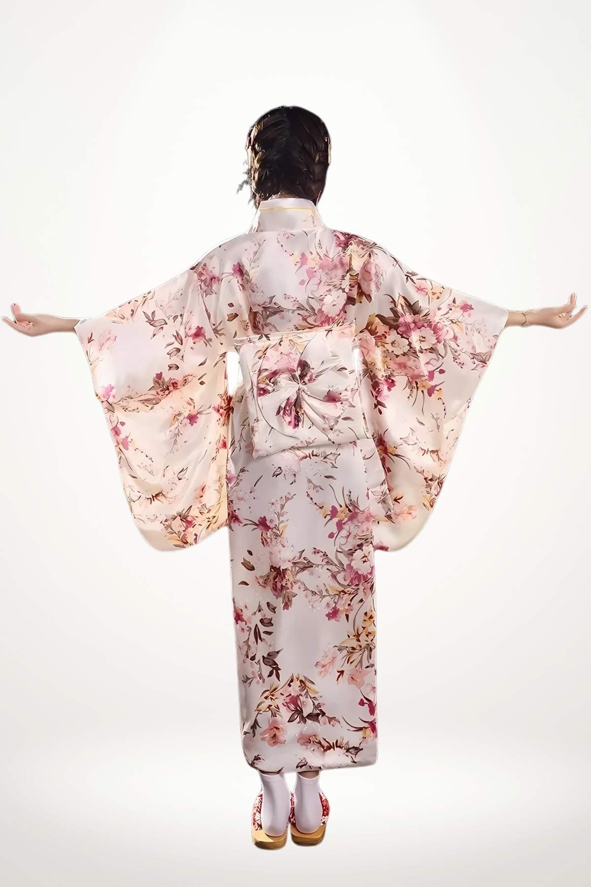 Femme en kimono long en satin pastel à motifs floraux japonais, coupe traditionnelle et ceinture tressée.
