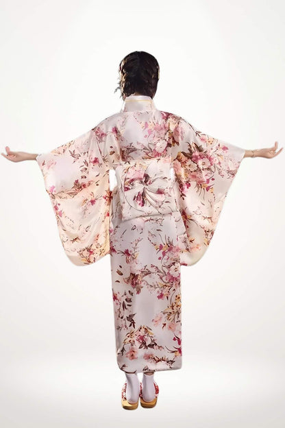 Femme en kimono satin aux motifs floraux roses, bras écartés, sur fond blanc lumineux