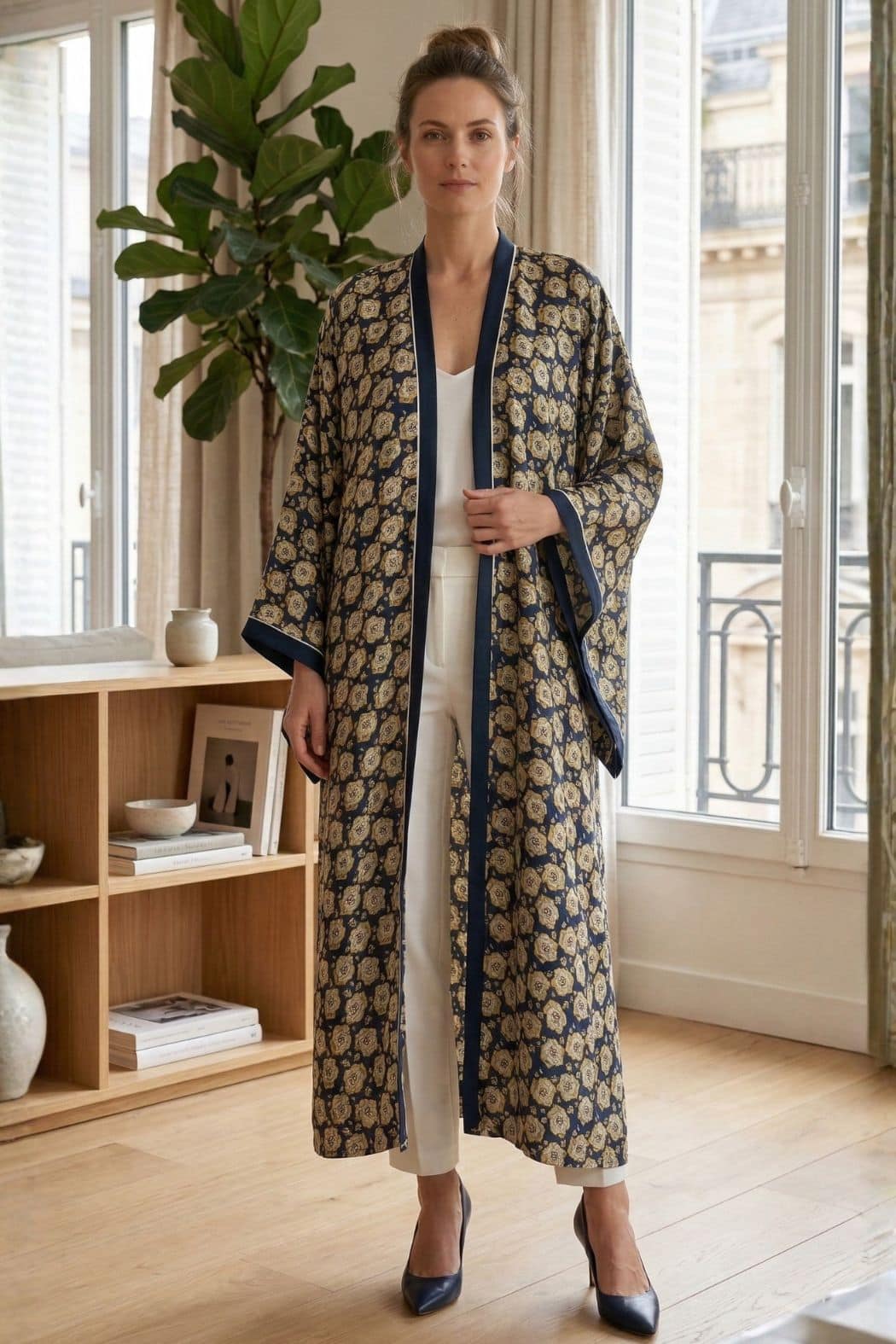 Femme en kimono satin à motifs floraux, bleu et doré, se tenant dans un intérieur lumineux et élégant