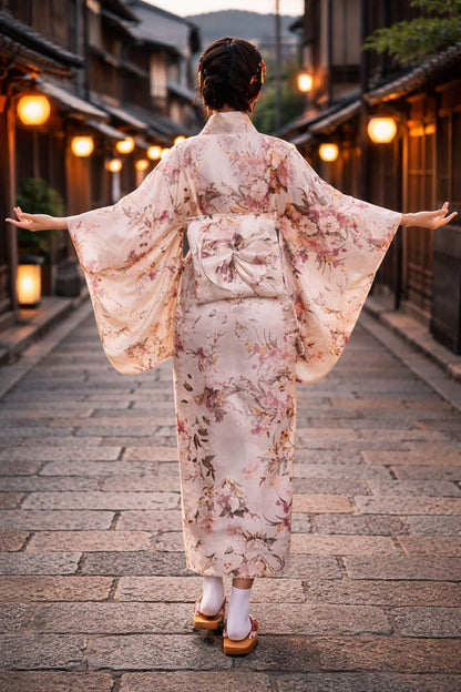 Femme en kimono satin aux motifs floraux, se tenant dans une rue pavée, éclairée par des lanternes