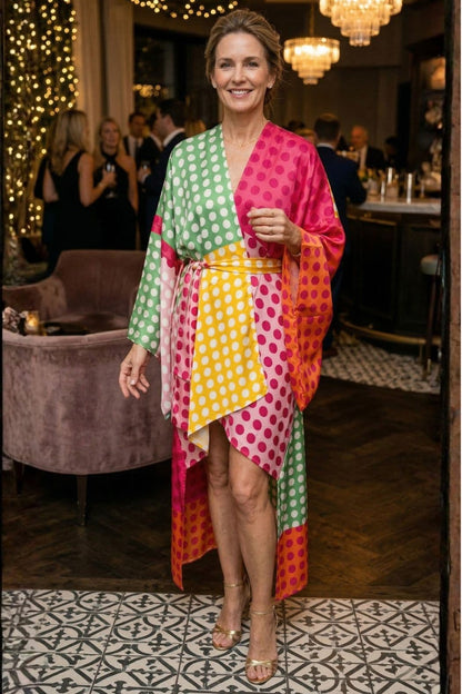 Femme souriante en kimono satin coloré à pois, se tenant debout dans un décor élégant avec un bar en arrière-plan